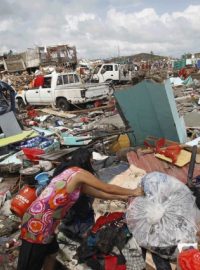 Žena si poblíž města Tacloban suší šaty na troskách tisíců zničených domů po průchodu supertajfunu Haiyan