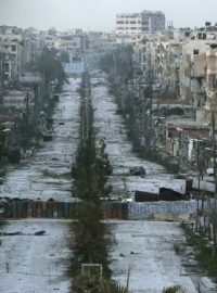 Pohled ukazuje zničenou ulici ve městě Aleppo, na které jsou jako bariéry vyskládané pytle s pískem