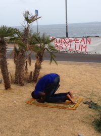 Migranti se modlí na břehu moře těsně před francouzskou hranicí