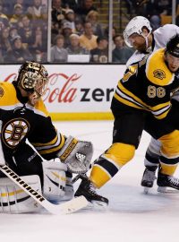 Bostonský brankář Tuukka Rask při zákroku proti dorážejícímu Philu Kesselovi v nočním zápase NHL