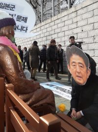 Aktivista s maskou japonského premiéra Abeho klečí u sochy sexuální otrokyně před japonským konzulátem v Pusanu.