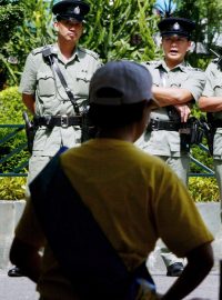 Policisté v Hongkongu dohlížejí na meditaci příznivců hnutí Fa-lun Kong, která proběhla během protestní hladovky v srpnu 2002. Hnutí je v Číně pronásledované.