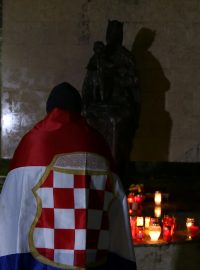 Bosenský Chorvat zabalený do vlajky Chorvatské republiky Herceg-Bosna se modlí za mrtvého Slobodana Praljaka.