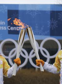 Dobrovolníci si předávají olympijský oheň