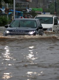 Auto projíždějí přes zaplavené silnice na západě Indie v Ahmedabádu.