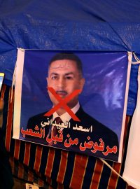 Demonstrant u plakátu, na němž je guvernér Basry a kandidát na premiéra Asaad Ajdání. Toho protestující odmítají