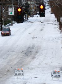 Auto pomalu sjíždí z kopce na uzavřené Queen Anne Avenue North, po silném sněžení v Seattlu.