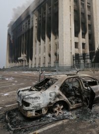 Shořelé auto před budovou radnice v kazašském Almaty, která byla během protestů zapálena