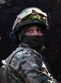 Ukrajinský voják poslouchá v zákopech u Bachmutu dělostřeleckou palbu