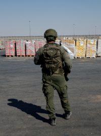 Izraelský voják stojí vedle balíků s humanitární pomocí, které čekají na převoz z Izraele do Gazy