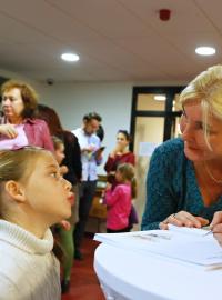 Michaela Vetešková podepisuje knihu malé čtenářce.