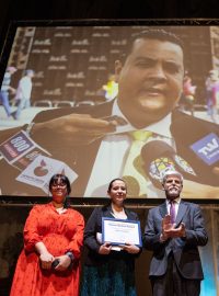 Předání ceny Homo Homini během zahájení festivalu Jeden svět. Na snímku Clara Ramírez (druhá zleva), ředitelka nadace FundaRedes, prezident Petr Pavel a ředitel Člověka v tísni Šimon Pánek. Na obrazovce fotografie vězněného venezuelského aktivisty Javiera Tarazony
