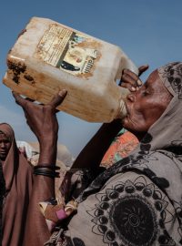 Šedesátiletá žena pije v somálském městě Baidoa vodu ze špinavého barelu