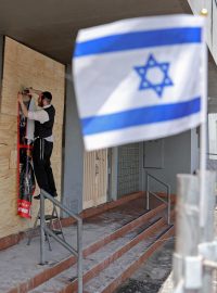 Člen židovské komunity připevňuje plakát na průčelí poškozené synagogy v Melbourne