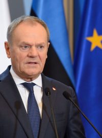 Polský premiér Donald Tusk s polskou, estonskou a unijní vlajkou v pozadí.