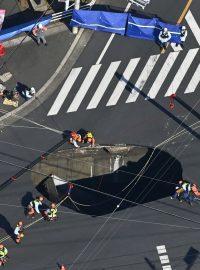 Japonští záchranáři se snaží vyprostit řidiče, který spadl do díry v silnici